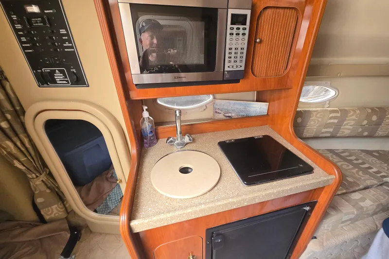 Slide: The Image of 2005 Rinker Fiesta Vee 270 interior kitchen with microwave, sink, and stove. - 22