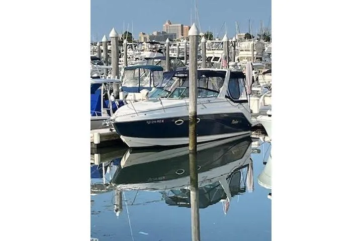 Slide: The Image of 2005 Rinker Fiesta Vee 270 boat docked in a marina, reflecting on calm water. - 3