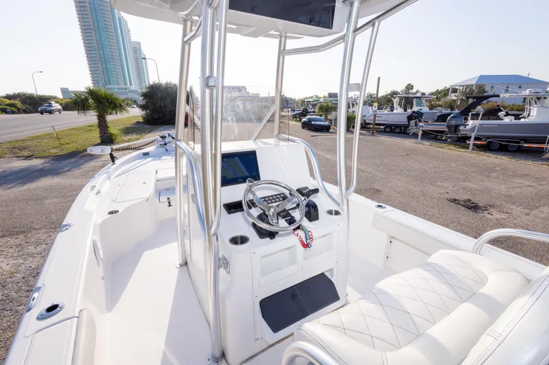 Slide: The Image of 2021 Blue Wave 2600 PureBay boat interior with steering console and seating, parked near a road. - 15
