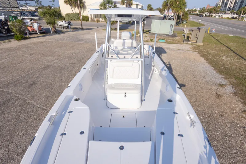 Slide: The Image of 2021 Blue Wave 2600 PureBay boat with spacious deck and seating, parked outdoors. - 25