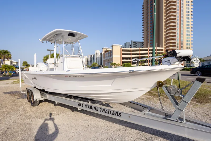 Slide: The Image of 2021 Blue Wave 2600 PureBay boat on trailer, urban backdrop, sunny day. - 3