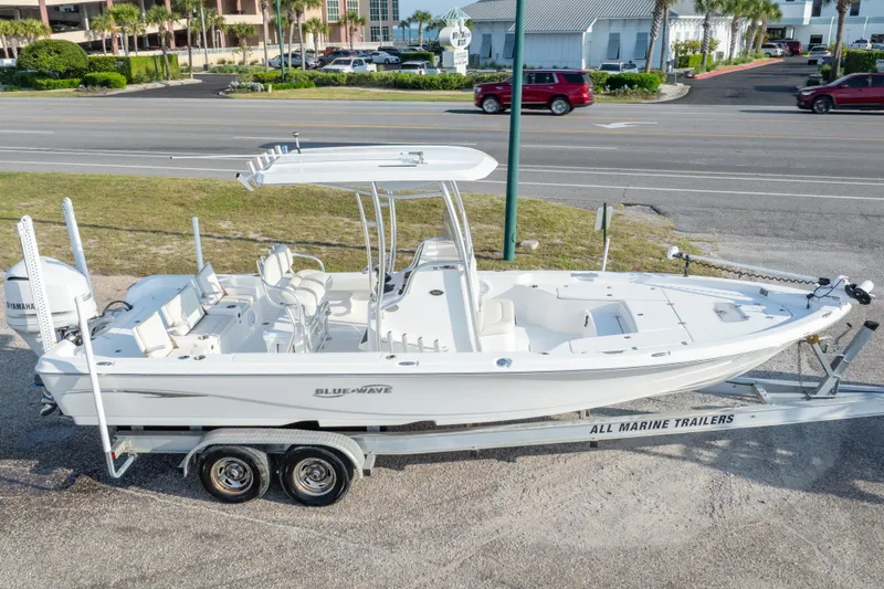 Slide: The Image of 2021 Blue Wave 2600 PureBay boat on trailer, parked near a road with palm trees. - 39