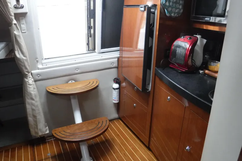 Slide: The Image of 2006 Regal Commodore 3560 IO yacht interior with wooden cabinetry and compact kitchen area. - 12