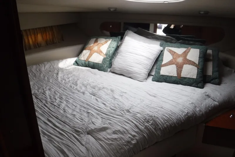 Slide: The Image of 2006 Regal Commodore 3560 IO cabin with starfish-themed pillows on a cozy bed. - 19
