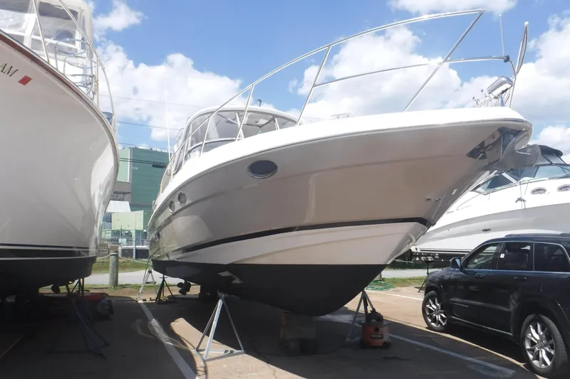 Slide: The Image of 2006 Regal Commodore 3560 yacht on stands, parked beside vehicles under a clear sky. - 31