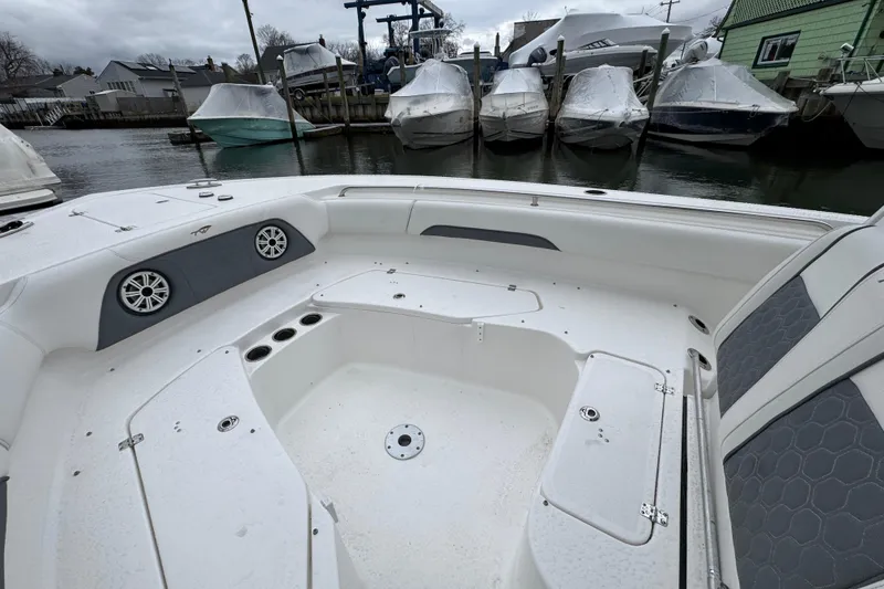 Slide: The Image of 2018 Tidewater 252 LXF boat interior with seating and cup holders, docked near covered boats. - 10