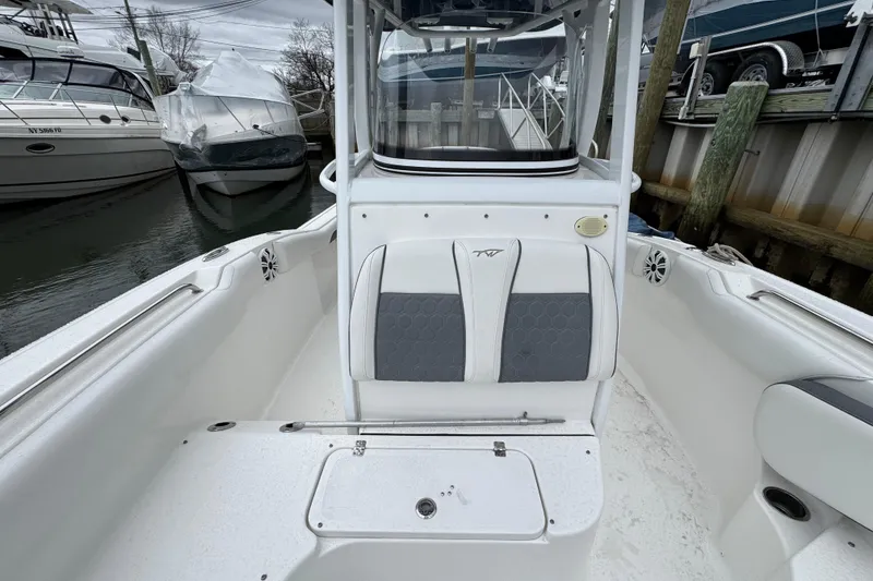 Slide: The Image of 2018 Tidewater 252 LXF boat interior with seating and storage, docked near other boats. - 11