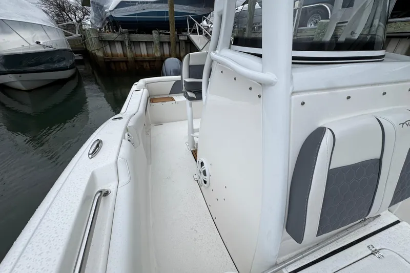 Slide: The Image of 2018 Tidewater 252 LXF boat interior, featuring sleek seating and modern design in a marina setting. - 17