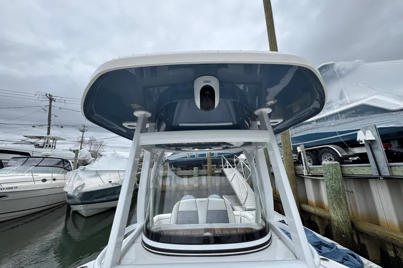 Slide: The Image of 2018 Tidewater 252 LXF boat with T-top, docked in marina under cloudy sky. - 18