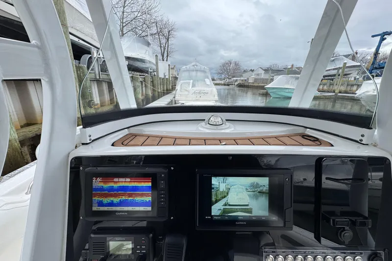 Slide: The Image of 2018 Tidewater 252 LXF boat dashboard with Garmin navigation screens, docked in a marina. - 20