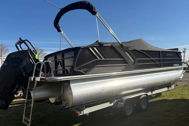 Slide: The Image of 2022 Crest Continental 250 pontoon boat on trailer, featuring sleek black design and powerful outboard motor. - 2