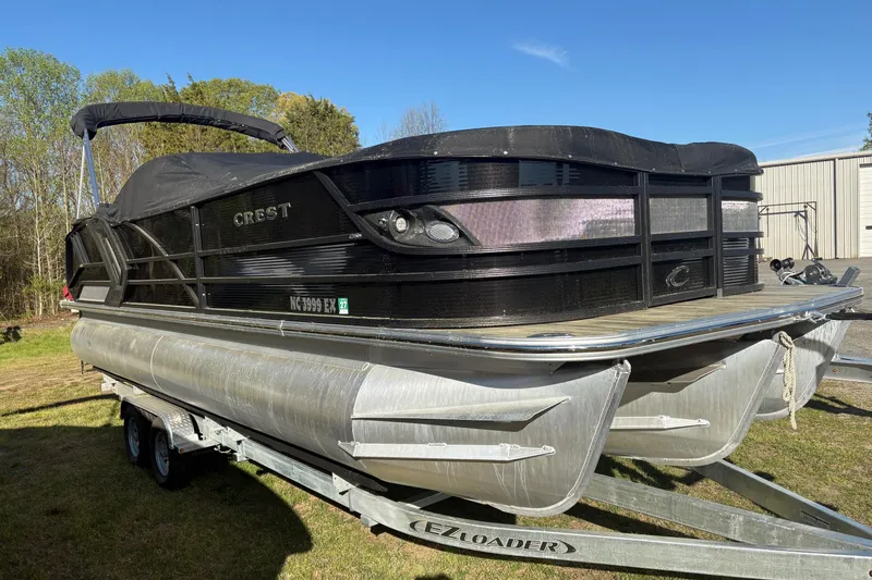Slide: The Image of 2022 Crest Continental 250 pontoon boat on trailer, covered and parked outdoors. - 3