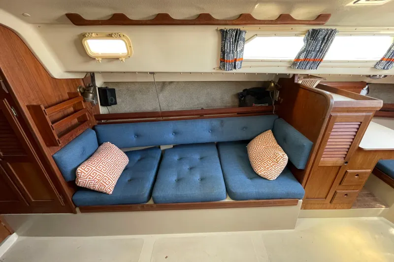 Slide: The Image of Interior of 1982 O'Day 34 sailboat with blue cushioned seating and decorative pillows. - 24