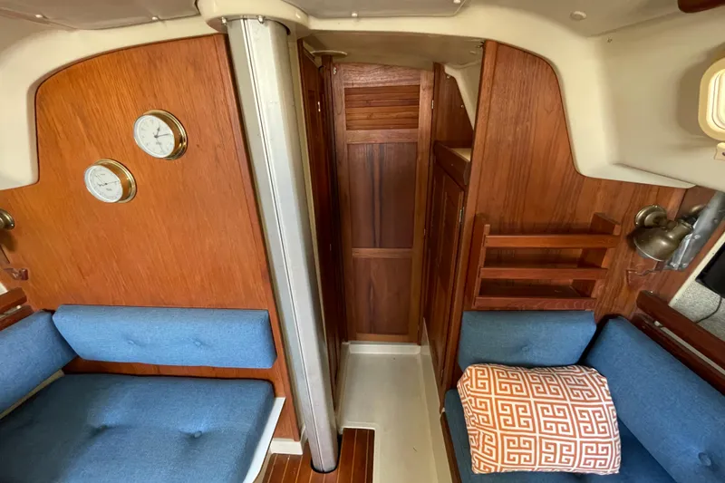Slide: The Image of Interior of 1982 O'Day 34 sailboat with blue cushioned seating and decorative pillow. - 25