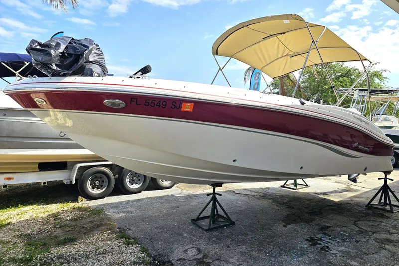 Slide: The Image of 2014 Hurricane SunDeck Sport 203 OB boat on stands, featuring a red and white hull. - 2