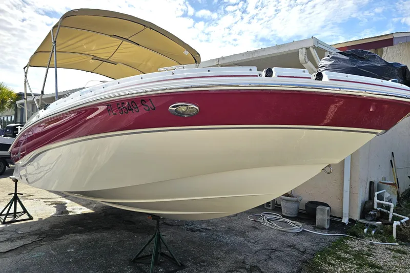 Slide: The Image of 2014 Hurricane SunDeck Sport 203 OB boat with red and white hull, parked on stands. - 3