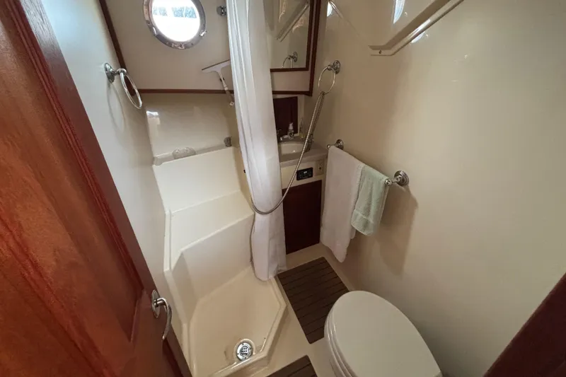 Slide: The Image of Compact bathroom in 2007 Nordic Tug 32, featuring shower, toilet, and porthole window. - 11