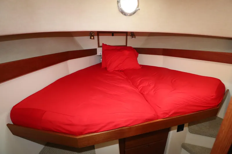 Slide: The Image of Cozy cabin interior of 2007 Nordic Tug 32 with red bedding and wooden accents. - 12