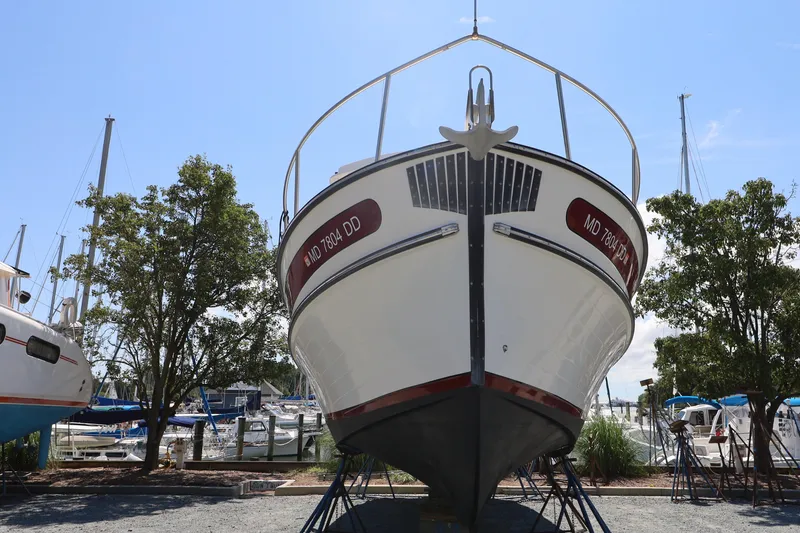 Slide: The Image of 2007 Nordic Tug 32 boat on dry dock, surrounded by trees and other boats. - 17