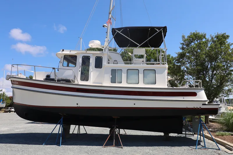 Slide: The Image of 2007 Nordic Tug 32 boat on dry dock, white with red accents, under clear blue sky. - 19