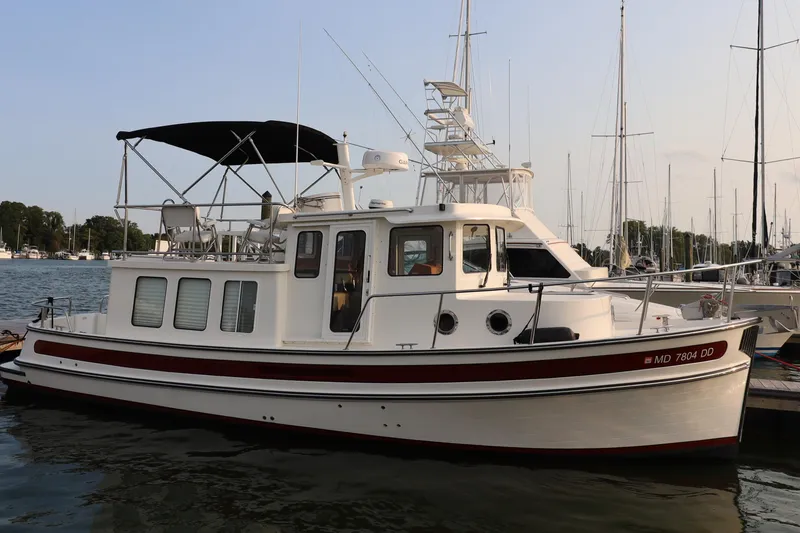Slide: The Image of 2007 Nordic Tug 32 docked at a marina, featuring classic design and spacious deck. - 2