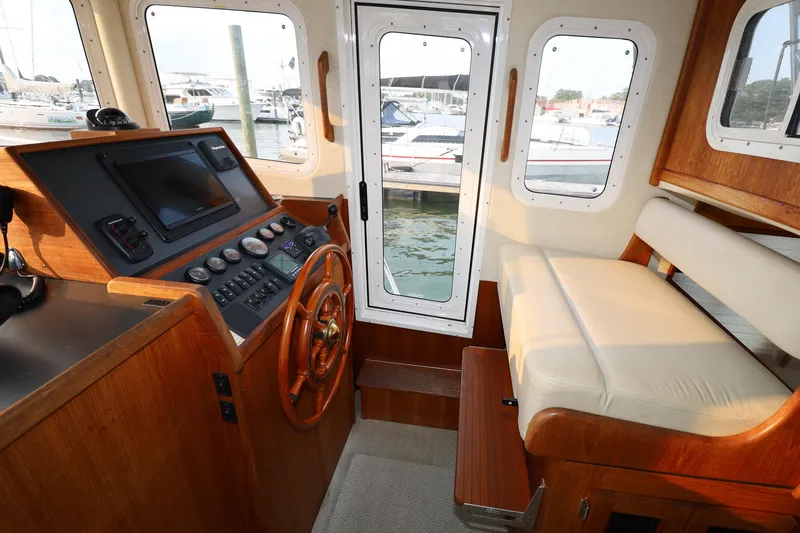 Slide: The Image of 2007 Nordic Tug 32 interior helm with wooden steering wheel and navigation controls. - 9