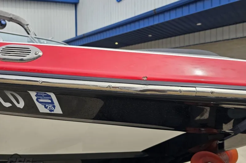 Slide: The Image of 2013 MasterCraft X-10 boat with red and black hull, docked near a building. - 18