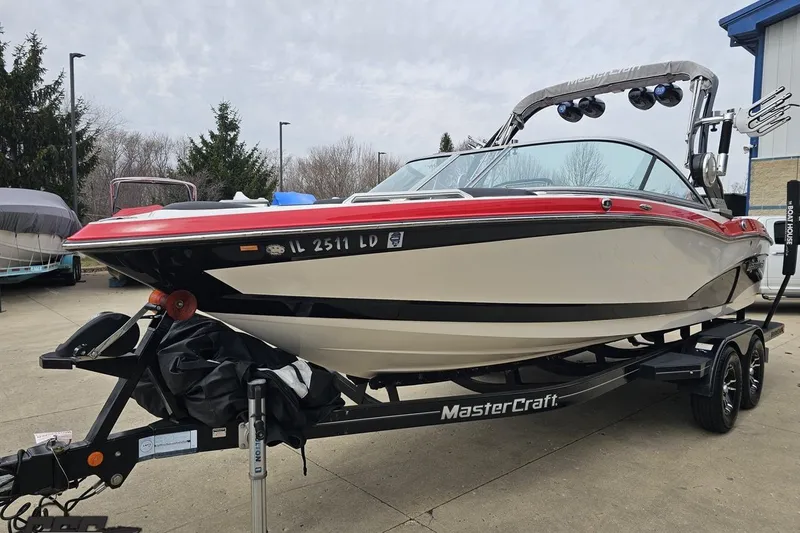 Slide: The Image of 2013 MasterCraft X-10 boat on trailer, red and white design, parked outdoors. - 22