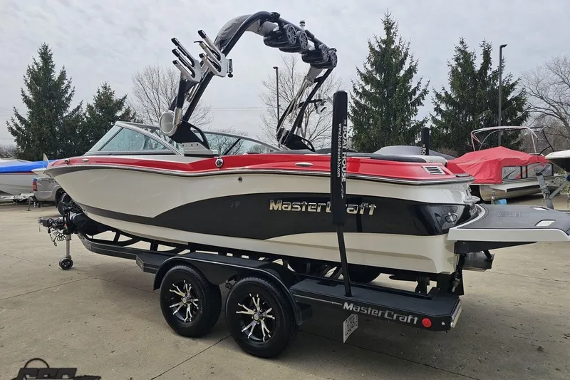 Slide: The Image of 2013 MasterCraft X-10 boat on trailer, red and white design, parked outdoors. - 31