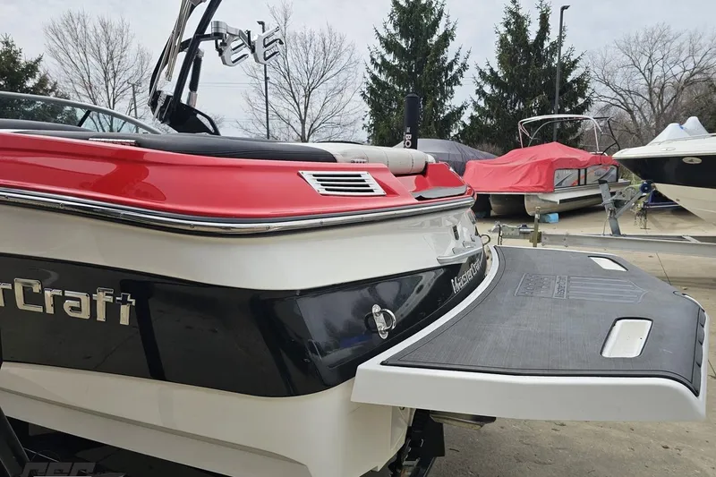 Slide: The Image of 2013 MasterCraft X-10 boat with red and black design, docked outdoors. - 33