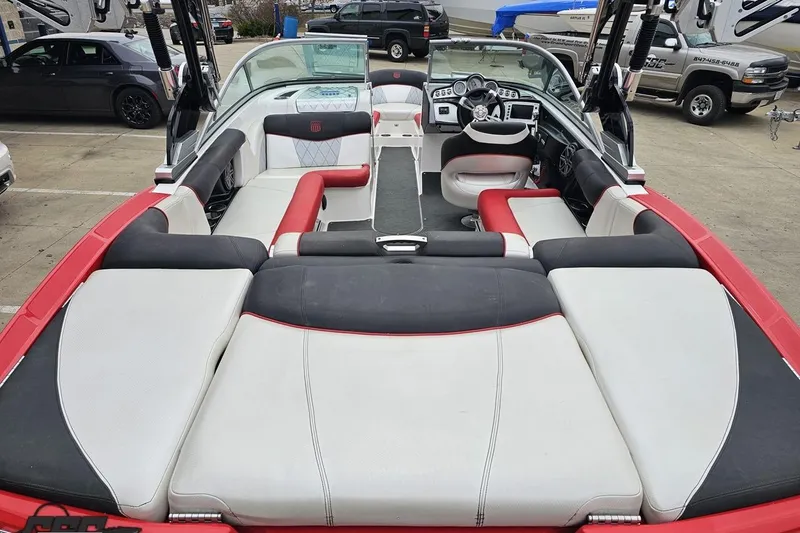 Slide: The Image of 2013 MasterCraft X-10 boat interior with red, black, and white seating, parked outdoors. - 43