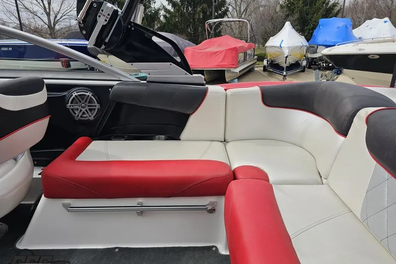 Slide: The Image of 2013 MasterCraft X-10 boat interior with red and white seating, parked among covered boats. - 51