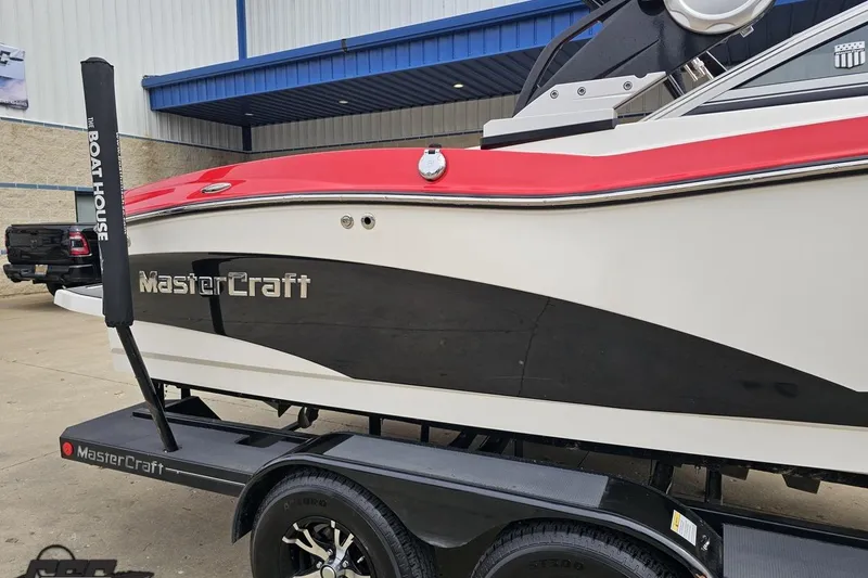 Slide: The Image of 2013 MasterCraft X-10 boat with red and black design on a trailer. - 7