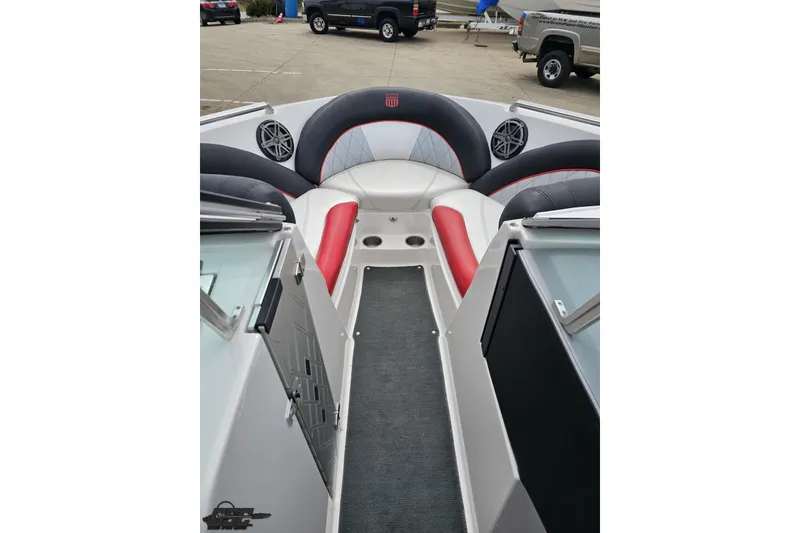 Slide: The Image of 2013 MasterCraft X-10 boat interior with red and black seating, speakers, and carpeted walkway. - 75
