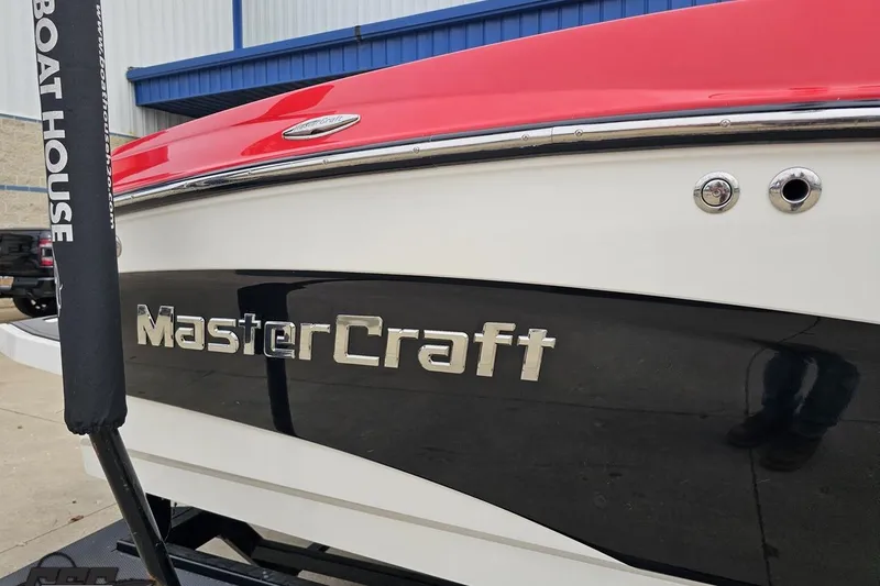 Slide: The Image of 2013 MasterCraft X-10 boat with red and black exterior, parked near a building. - 8