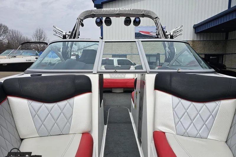 Slide: The Image of 2013 MasterCraft X-10 boat interior with red and white seating, docked outdoors. - 84