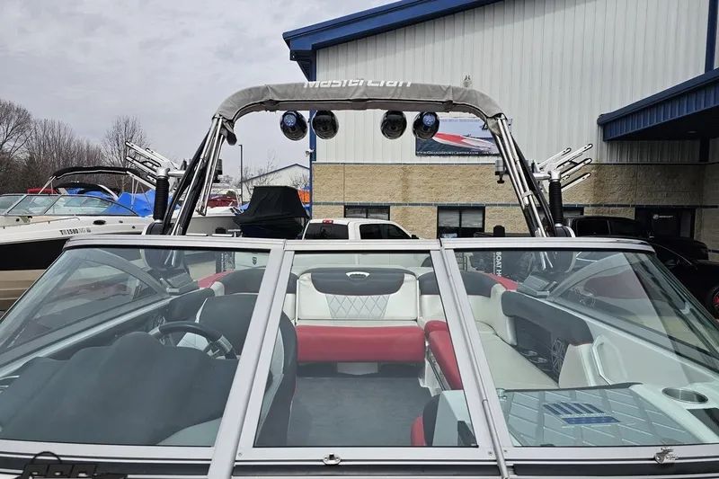 Slide: The Image of 2013 MasterCraft X-10 boat with red and white interior, parked outdoors near a building. - 85