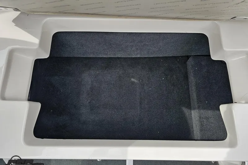 Slide: The Image of Storage compartment of a 2013 MasterCraft X-10 boat, featuring a clean, carpeted interior. - 96