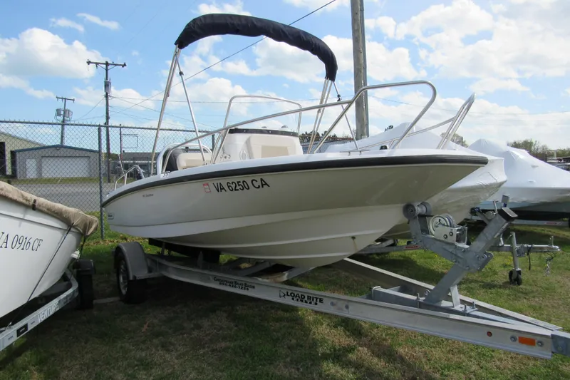 Slide: The Image of 2017 Boston Whaler 180 Dauntless boat on trailer, parked outdoors under blue sky. - 12