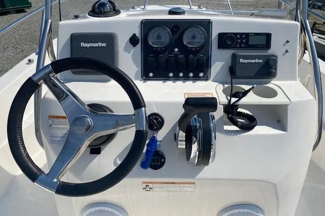 Slide: The Image of 2017 Boston Whaler 180 Dauntless boat on trailer, parked outdoors near blue building. - 3