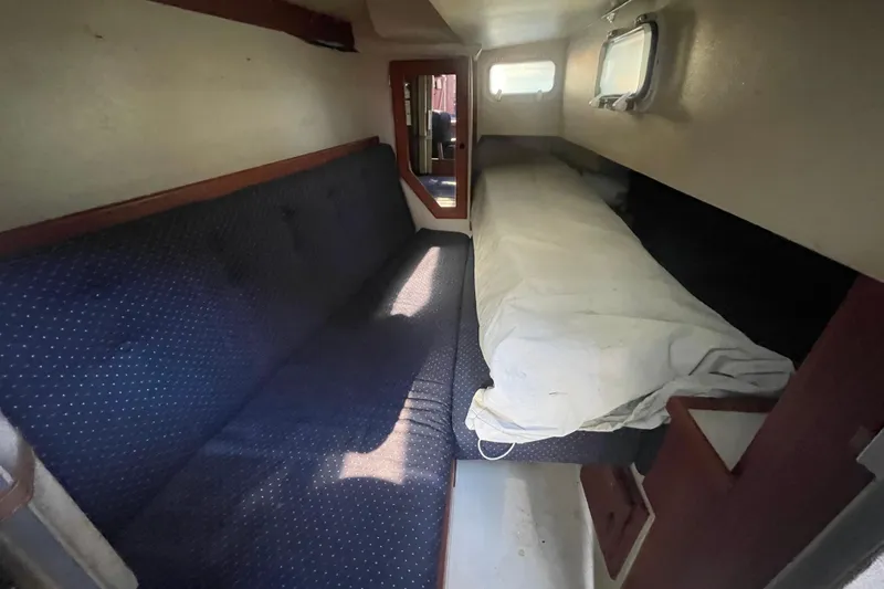 Slide: The Image of Interior cabin of a 1989 Catalina 36 sailboat with blue seating and a small window. - 17