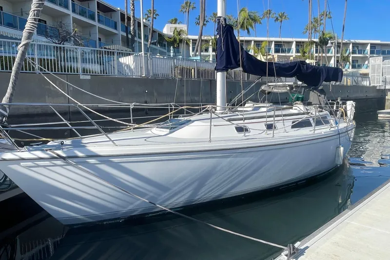 Slide: The Image of 1989 Catalina 36 sailboat docked in marina, surrounded by modern buildings and palm trees. - 2