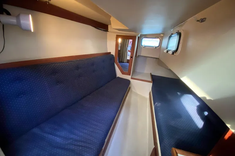 Slide: The Image of Interior of 1989 Catalina 36 sailboat with blue cushioned seating and porthole windows. - 25