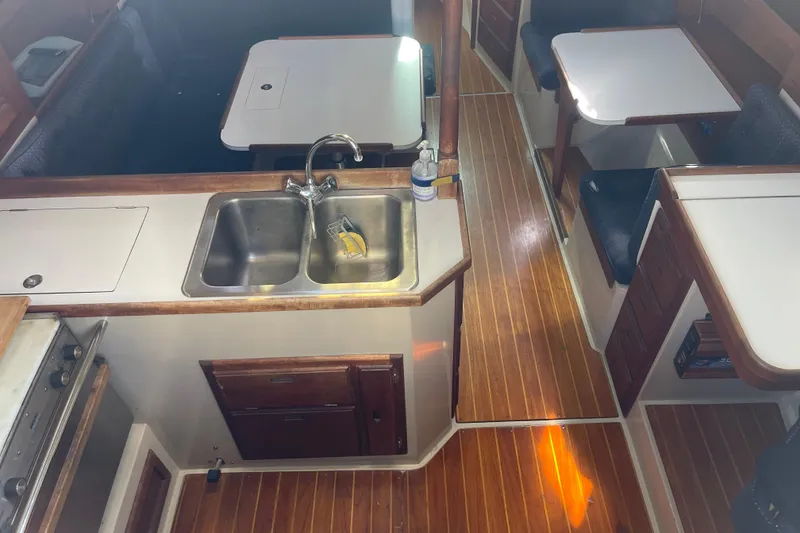 Slide: The Image of Interior of a 1989 Catalina 36 sailboat featuring a compact kitchen and dining area. - 6
