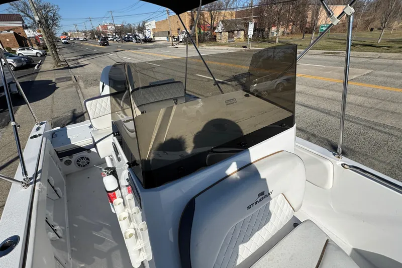 Slide: The Image of 2025 Stingray 173 CC boat interior with seating, windshield, and rod holders on a street. - 12