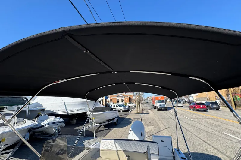 Slide: The Image of 2025 Stingray 173 CC boat with black canopy, parked on a sunny street. - 16