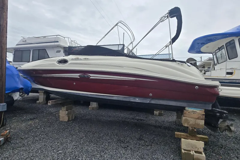 Slide: The Image of 2007 Sea Ray 240 Sundeck boat on blocks, red and white hull, marina background. - 1