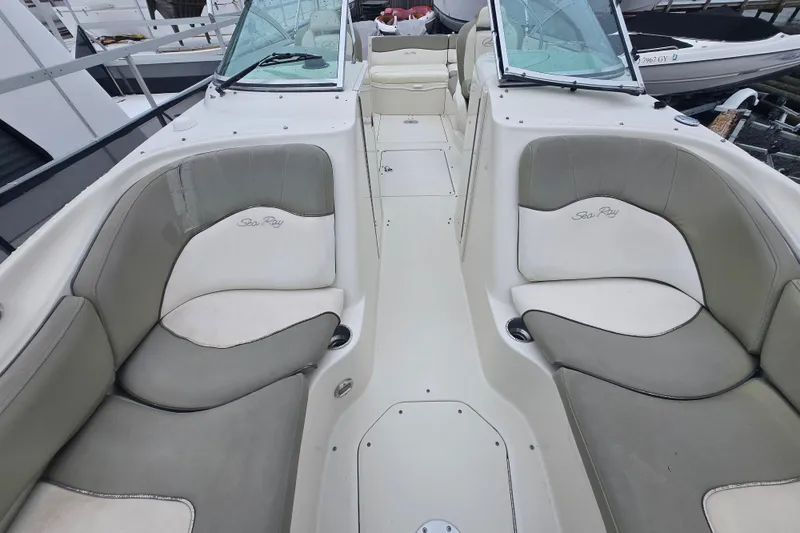 Slide: The Image of 2007 Sea Ray 240 Sundeck interior with cushioned seating and windshield, docked at marina. - 11