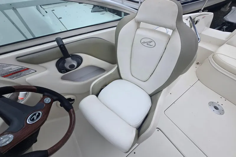 Slide: The Image of 2007 Sea Ray 240 Sundeck helm with white captain's chair and steering wheel. - 16