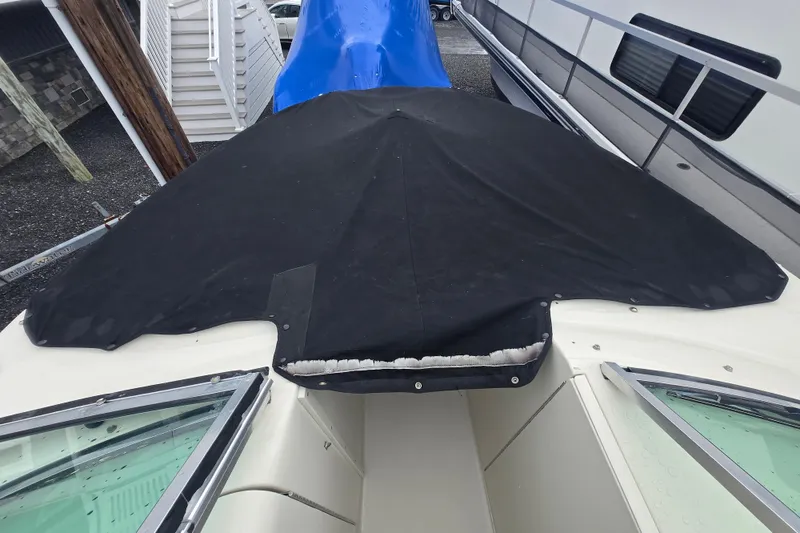 Slide: The Image of 2007 Sea Ray 240 Sundeck with black cover, docked beside other boats. - 18
